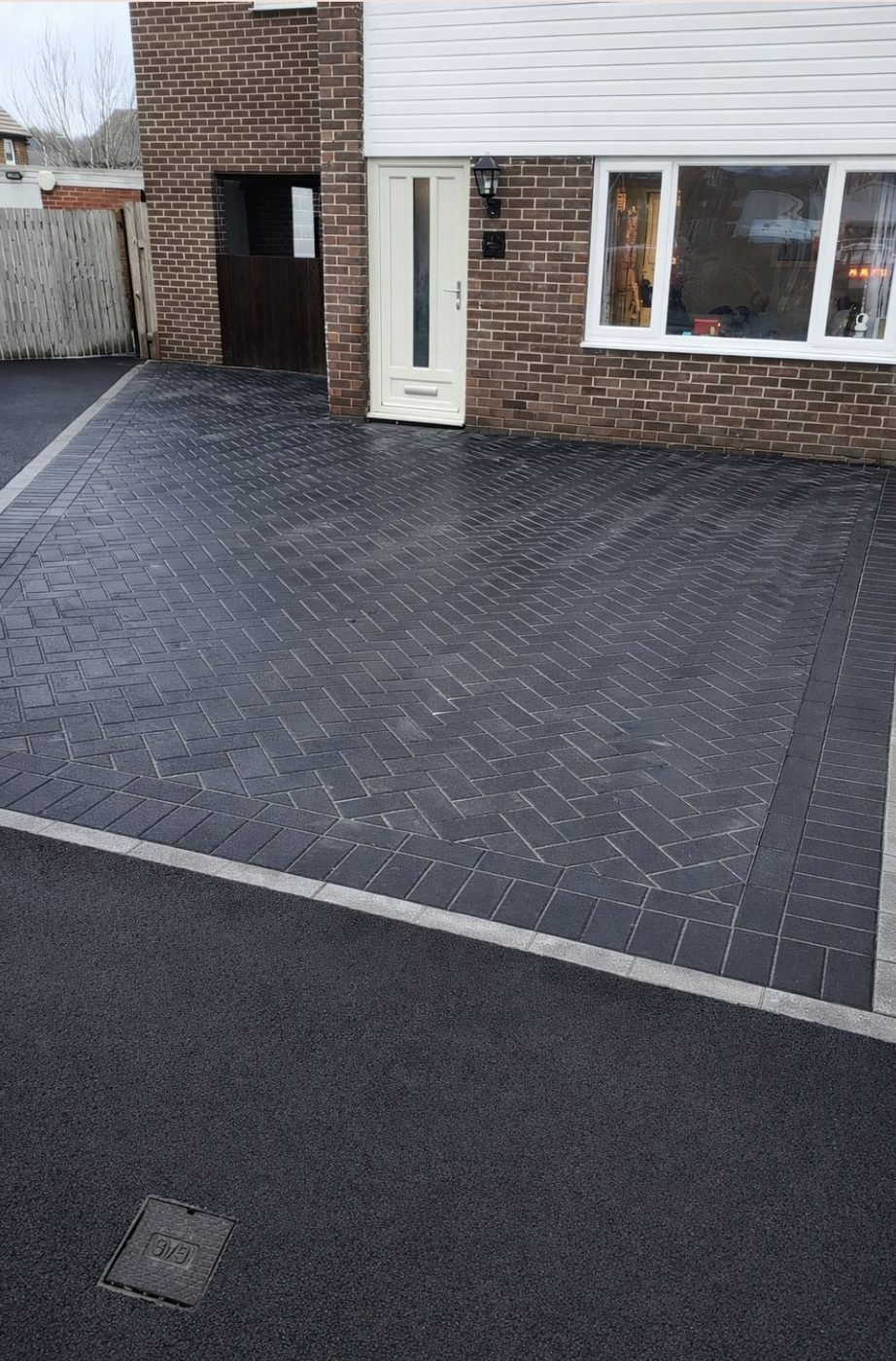 Charcoal block paved driveway laid in herringbone with a light soldier course border