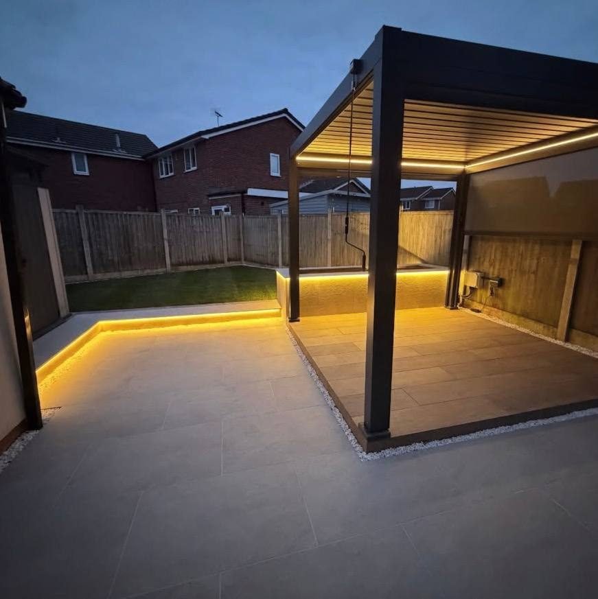 Aluminium pergola and porcelain patio lit at dusk with warm strip lighting under the seating wall